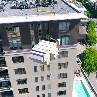 Image of a crane lifting a new HVAC unit to a roof