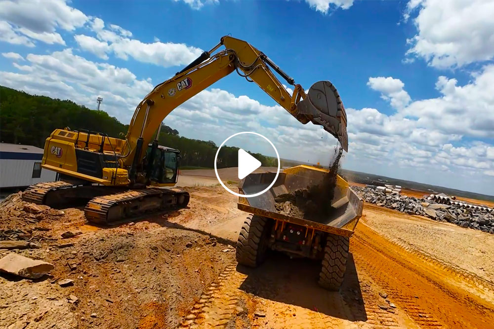 Backhoe dumping dirt on a dump truck